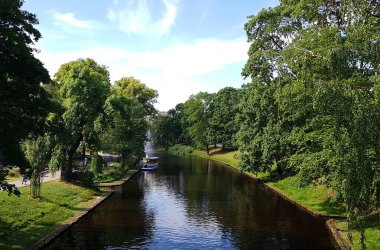 Yazın şehir parkındaki ağaçların arasında tekne gezisi için dar bir kanal.