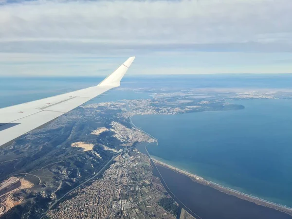 Křídlo létajícího letadla na pozadí panoramatu země a moře — Stock fotografie