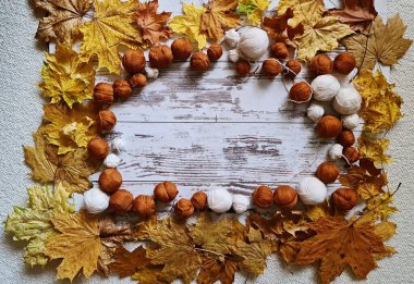 Masadaki sarı akçaağaç yaprakları arasında bir sürü beyaz ve bej örgü ipliği var..