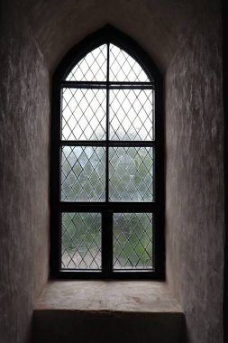 Narrow glazed window in the thick stone wall of the old castle.