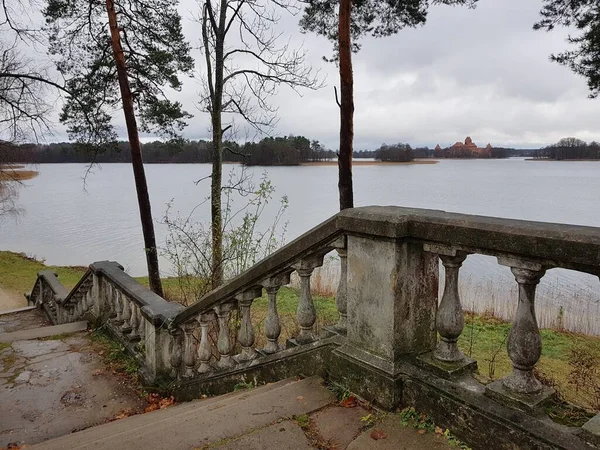 An old stone staircase on the lake shore and a panorama with a view of the Trakai Island Castle in Lithuania on November 18, 2018.