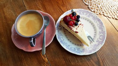 Sade kahve ve çay tabağında taze böğürtlenli bir dilim kek devre arası kahvesi için hazırlanır..