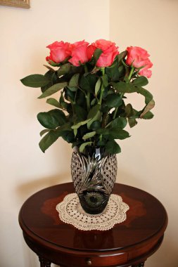 Odadaki küçük bir masada kristal bir vazoda güzel kırmızı güller..