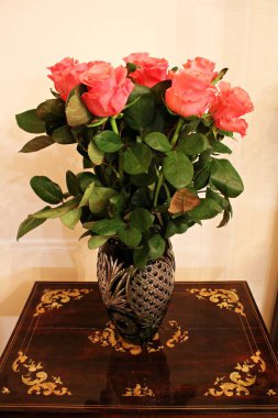 Odadaki küçük bir masada kristal bir vazoda güzel kırmızı güller..