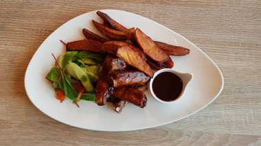 Kızarmış sığır kaburgası, patates, kırmızı sos ve taze salata..