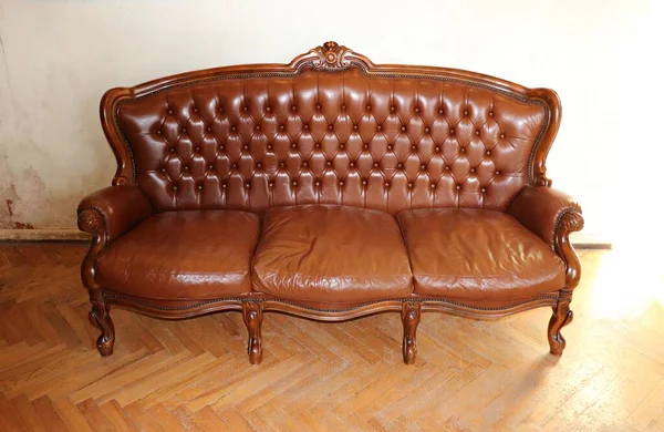 Hellbraunes Retro-Ledersofa an der Wand im Zimmer eines alten Hauses — Stockfoto