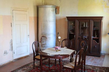 Seramik bir sürahide küçük bir buket çiçek eski bir evin odasındaki yuvarlak bir masada..