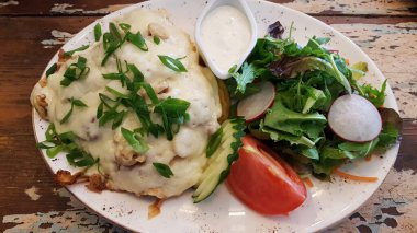 Peynirli kızarmış domuz eti ve beyaz tabakta taze sebze salatası..