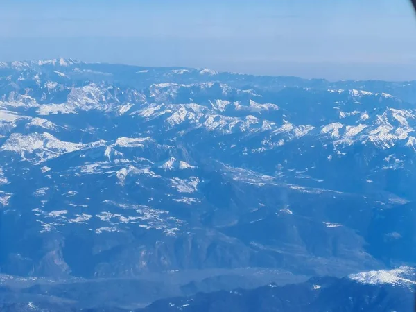 Üzerlerinde uçan bir uçağın camındaki kar kaplı Alpler Panoraması.