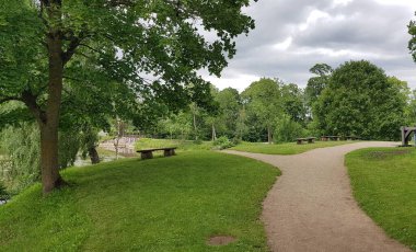 Bir yaz günü küçük bir gölet boyunca ağaçların arasında yürümek için ısıtma yolları.