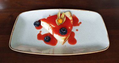 Süzme peynirli turta, yaban mersini ve beyaz tabakta çilek reçeli.