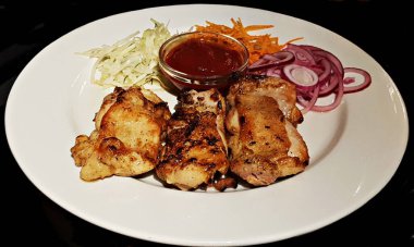 Üç parça kızarmış tavuk ketçapı beyaz bir tabakta küçük bir cam prizde..