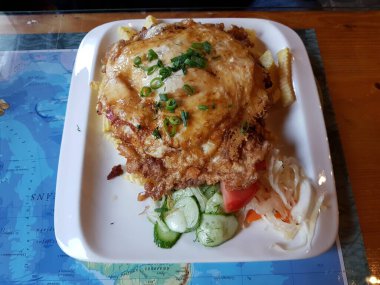 Tavada pişmiş büyük bir parça domuz pirzolası ve tabakta taze sebze..