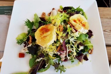 Beyaz tabakta taze yeşil yapraklı ceviz ve portakal salatası..