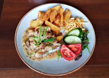 Kızarmış patates ve mantar soslu domuz eti. Beyaz tabakta taze sebze salatası..