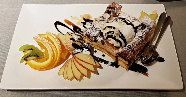 Elma dilimleri, portakal ve kivi ile beyaz tabakta lezzetli meyveli turta..