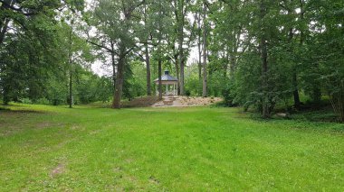 Yazın ağaçlık bir parkta küçük ahşap bir çardak. Letonya, Temmuz 2019.