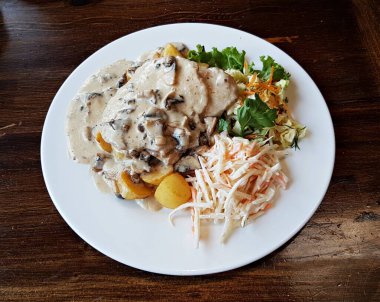 İki dilim mantar soslu pişirilmiş biftek, haşlanmış patates ve taze sebze salatası..