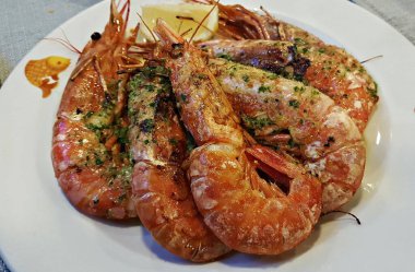 Beyaz bir tabakta pişmiş Langoustines sosu, sokak kafesinde limon..