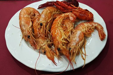 Beyaz bir tabakta pişmiş Langoustines sosu, sokak kafesinde limon..