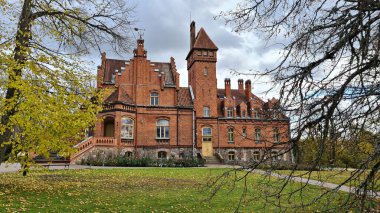 Old Latvian castle Jaunmoku made of red brick against the background of autumn trees in autumn 2021.