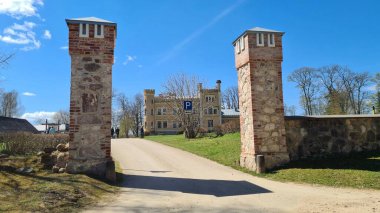 Old manor between stone pillars of the gate in the Latvian village of Garsene on a sunny May day 2022.