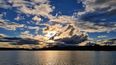Eylülde gün batımında bulutların ve geniş nehir yatağının önünde..