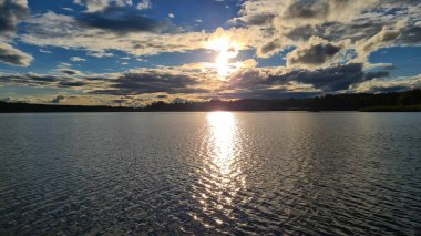 Eylülde gün batımında bulutların ve geniş nehir yatağının önünde..
