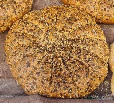 Yuvarlak bir somun lezzetli çavdar ekmeği ve masada tohumlar..