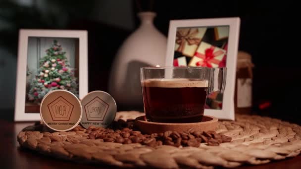 Egy csésze kávé két képkeret hátterén. Mellette gratulálunk az újévhez és a karácsonyhoz. — Stock videók