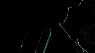 Kırık cam parçaları siyah arka planda farklı yönlere uçuyor..