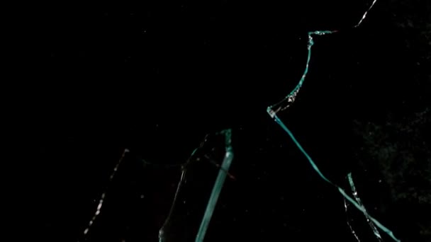 Fragments of broken glass fly in different directions on a black background. — Stockvideo