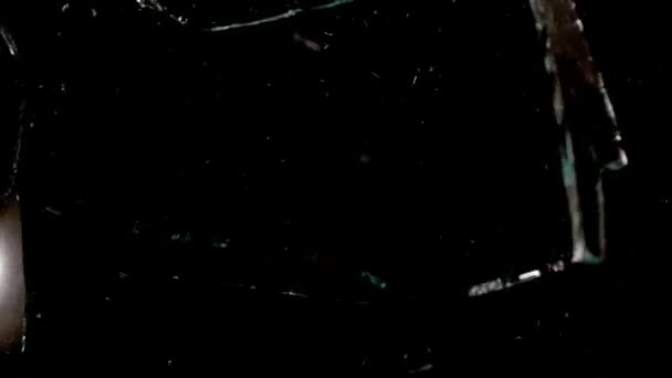 Fragments of broken glass fly in different directions on a black background. — Vídeo de Stock