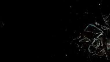 Kırık cam parçaları siyah arka planda farklı yönlere uçuyor..