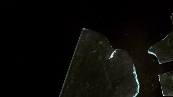 Fragmenty stłuczonego szkła latają w różnych kierunkach na czarnym tle. — Wideo stockowe