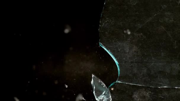 Fragmenten van gebroken glas vliegen in verschillende richtingen op een zwarte achtergrond. — Stockvideo