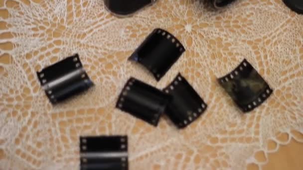 A vintage camera is lying on the table. Next to it is a 35 mm film cut into slides. — Stockvideo
