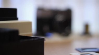 A vintage camera is lying on the table. Next to it is a 35 mm film cut into slides.