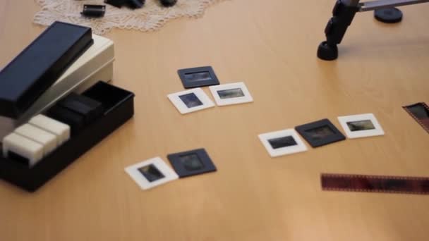 A vintage camera is lying on the table. Next to it is a 35 mm film cut into slides. — Stockvideo