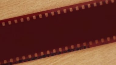 A vintage camera is lying on the table. Next to it is a 35 mm film cut into slides.