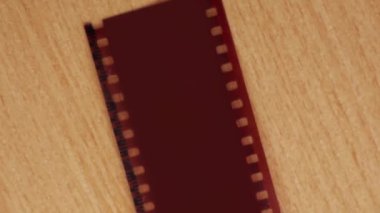 A vintage camera is lying on the table. Next to it is a 35 mm film cut into slides.