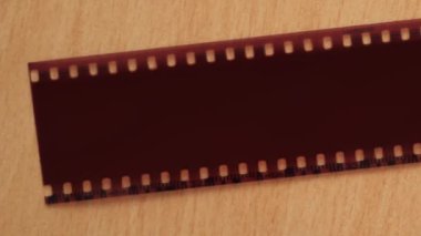 A vintage camera is lying on the table. Next to it is a 35 mm film cut into slides.