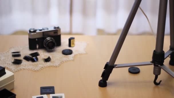 A vintage camera is lying on the table. Next to it is a 35 mm film cut into slides. — Stok video