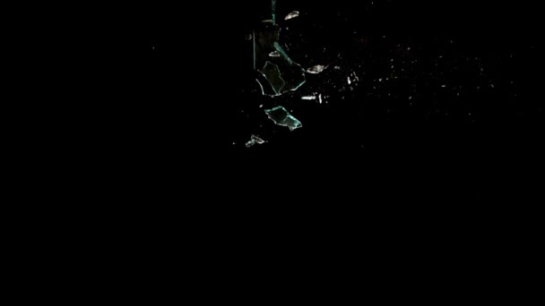 Fragments of broken glass fly in different directions on a black background. — Stockvideo
