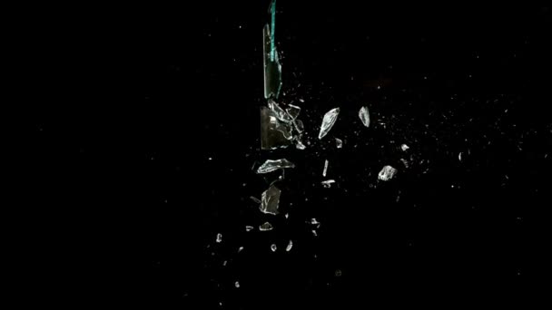 Fragmenty rozbitého skla létají různými směry na černém pozadí. — Stock video