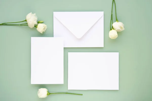 Beyaz düğün davetiyelerinin, zarfların ve beyaz çiçeklerin en iyi manzarası. El işi zarfı. Mavi arka plan. Düğün konsepti. Model