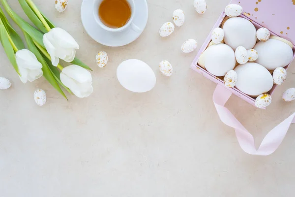 Laleli bir kutuda renkli yumurta manzarası bahar tatilinde bir fincan çay. Düz konum, bej arkaplan