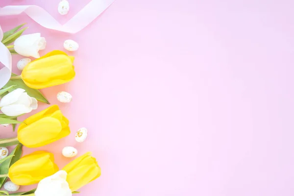 Paskalya kompozisyonu laleler ve paskalya yumurtaları. Pembe arka planda fotokopi alanı var. Düz yatış, üst görünüm