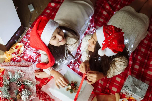 Noel şapkalı iki kız Noel hediyelerini paketliyor.