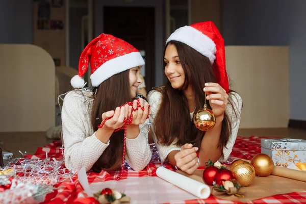 Noel şapkalı iki kız Noel hediyelerini paketliyor.